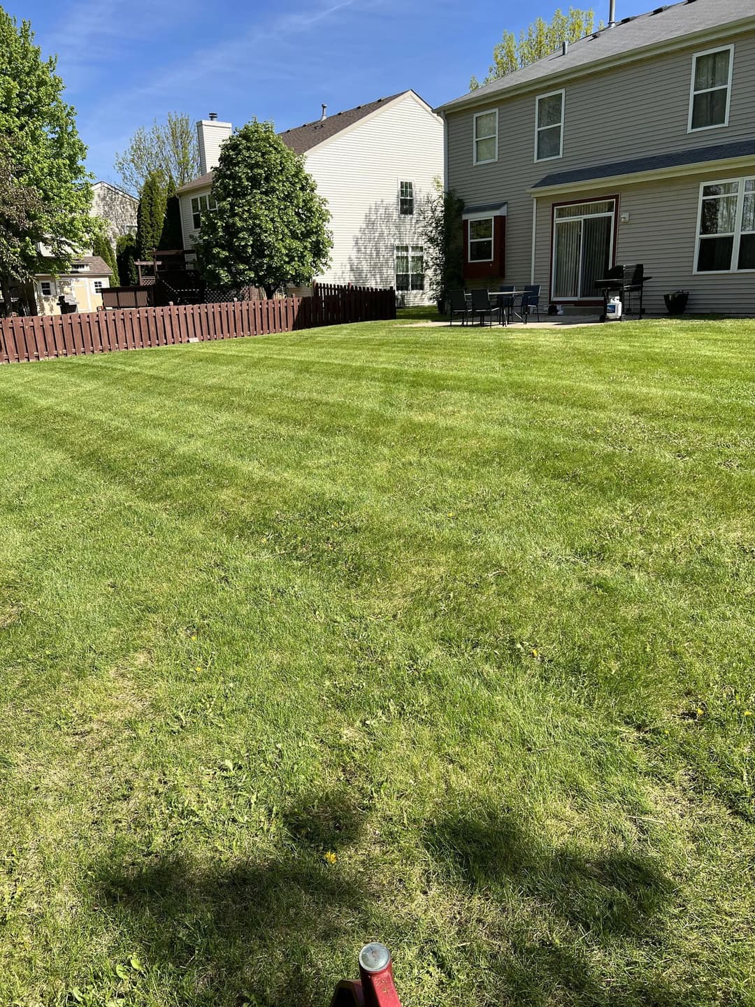 Lush green backyard with neatly mowed grass and a patio area. Ideal for outdoor relaxation.